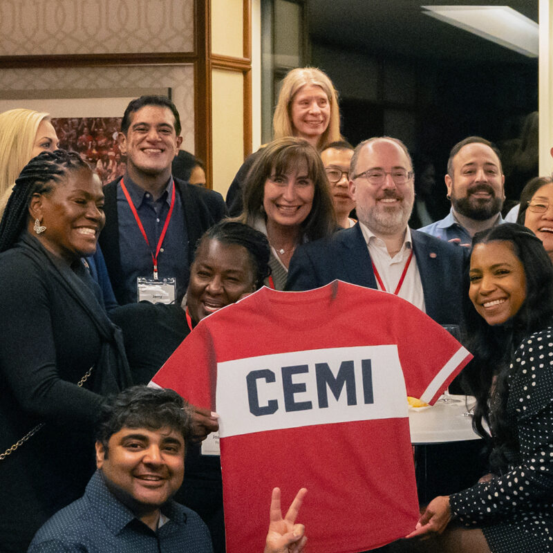a group of colleagues joke after the end of a kickoff meeting, posing with a jersey.