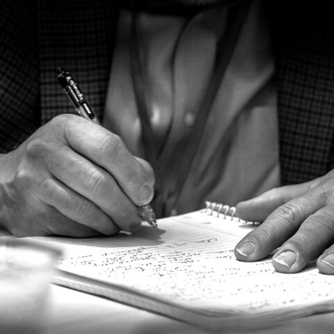 black and white photo of a person writing in a journal