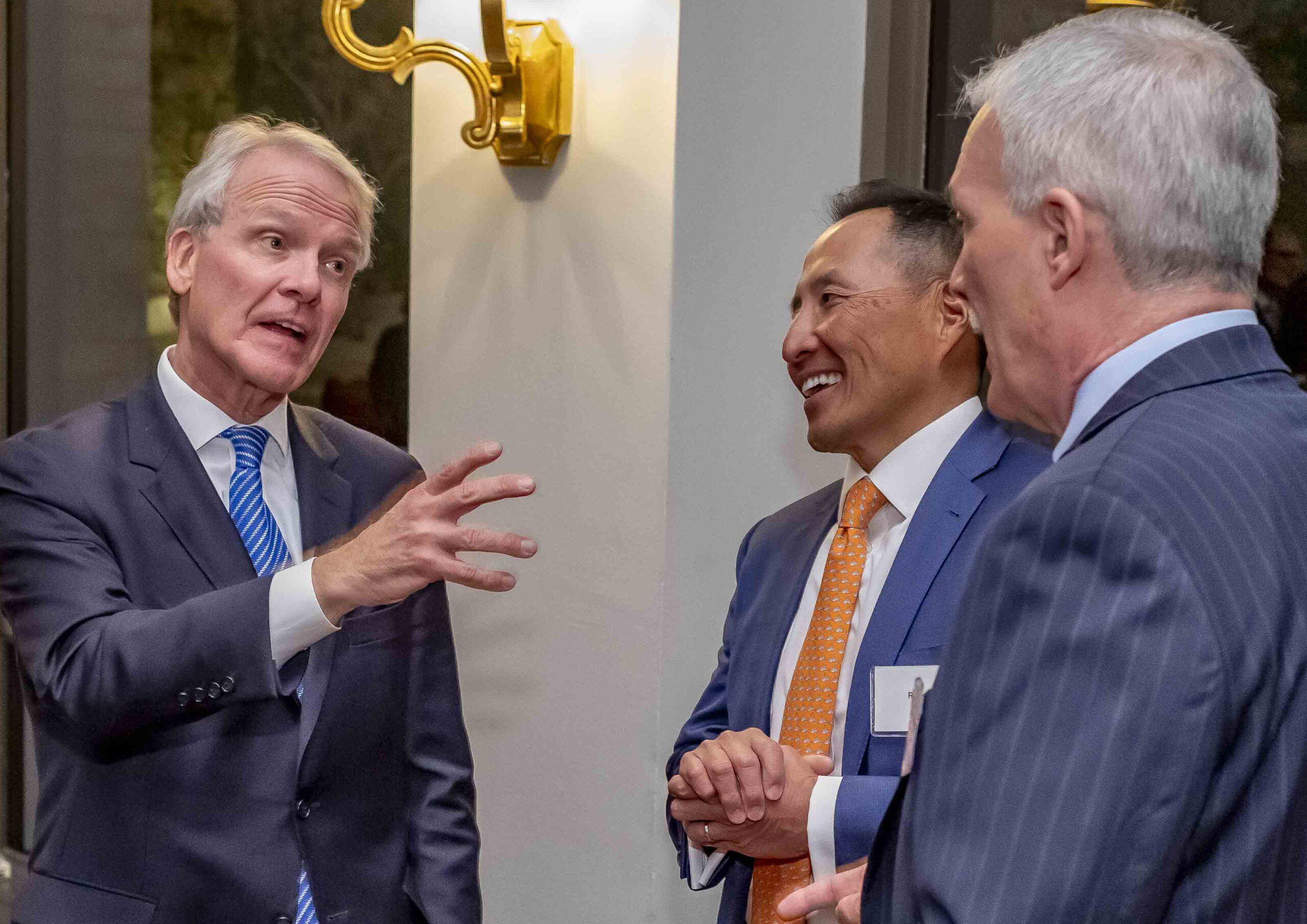 three men in conversation at a reception