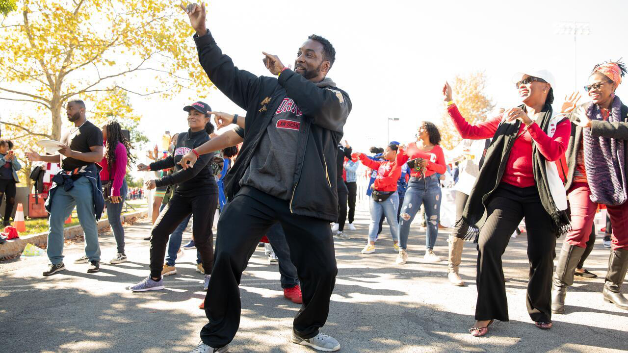 a group of alumni dance in the street during a reunion