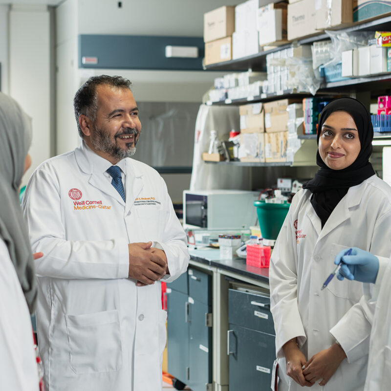 Weill Cornell Medicine-Qatar students and researchers talk in a lab.